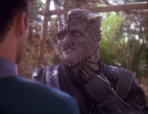 Jem Hadar pointing at his neck, where he has no ketracel white tube, in "Hippocratic Oath"